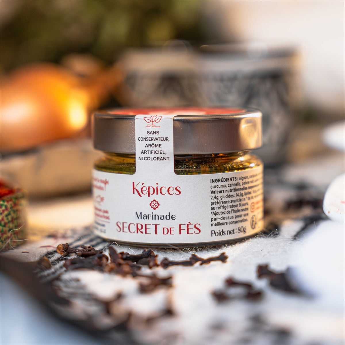 Pot de Marinade Secret de Fès Képices entouré de clous de girofle, paprika et herbes séchées.