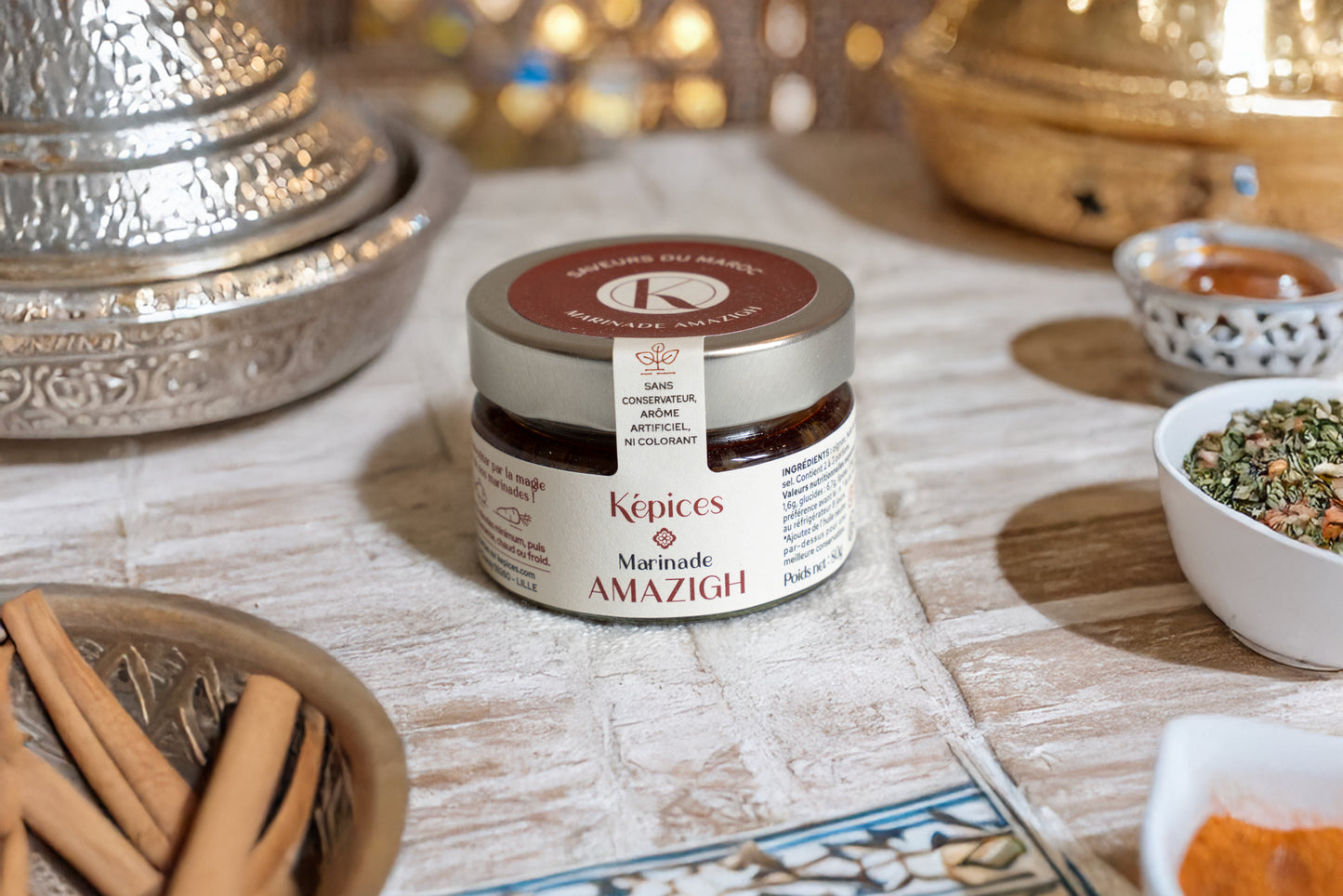 Pot de Marinade Amazigh Képices sur table orientale, accompagné de cannelle, coriandre et paprika.