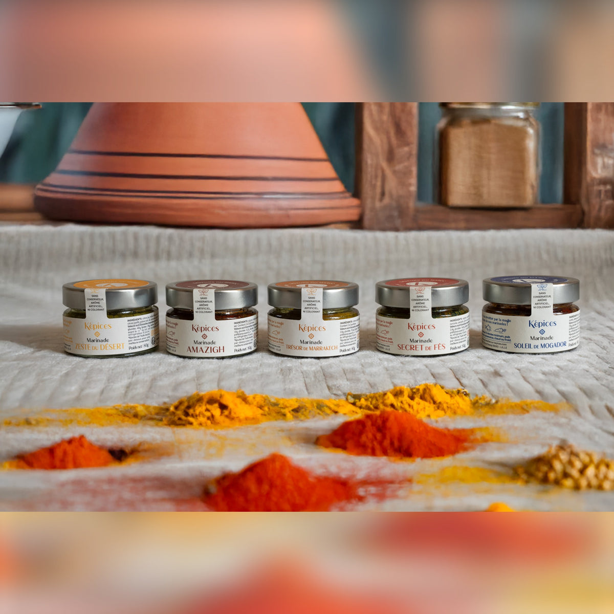 Présentation du Coffret Découverte Képices – cinq marinades marocaines artisanales alignées devant un plat à tajine et des épices en poudre.