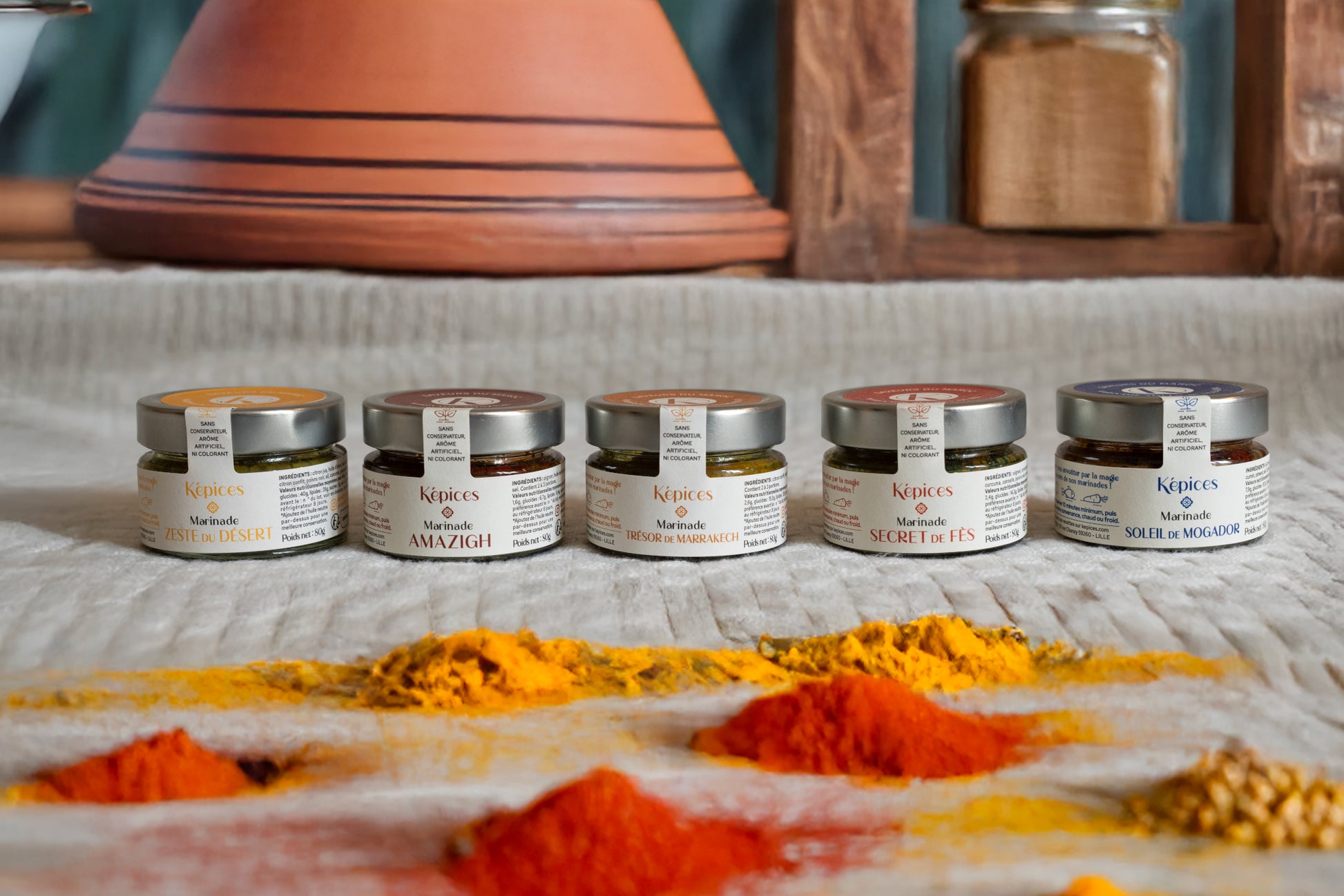 Présentation du Coffret Découverte Képices – cinq marinades marocaines artisanales alignées devant un plat à tajine et des épices en poudre.