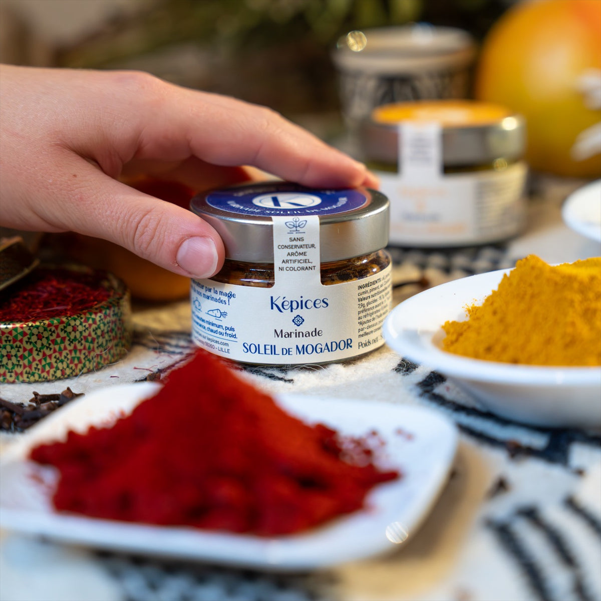 Présentation de la marinade marocaine Soleil de Mogador Képices sur une table avec des épices et des herbes fraîches