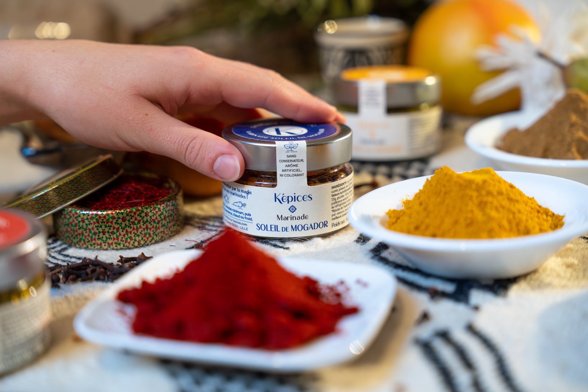 Présentation de la marinade marocaine Soleil de Mogador Képices sur une table avec des épices et des herbes fraîches