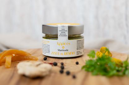 Pot de Marinade Zeste du Désert Képices sur planche en bois avec citron confit, gingembre et herbes fraîches.